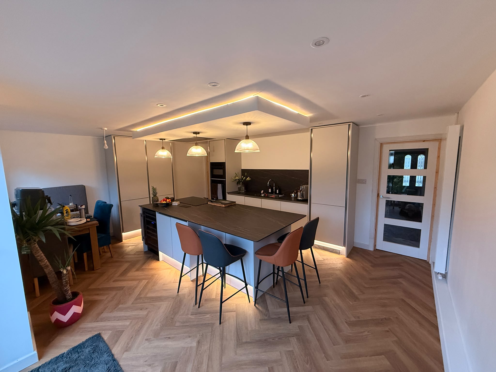Completed kitchen diner with island, herringbone flooring and LED ceiling feature — South Woodford